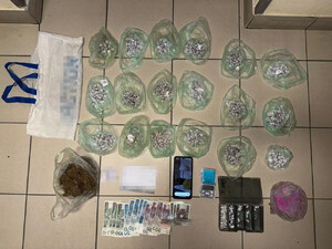 Zdjęcie przedstawia zabezpieczone różnego rodzaju środki odurzające, popakowane w torebki, wagę elektroniczną, banknoty oraz telefon komórkowy.