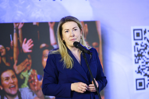 Zdjęcie przedstawia kobietę przed mikrofonem.