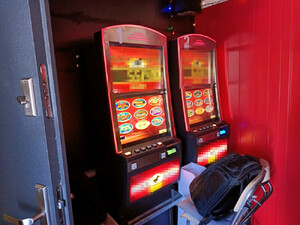 Zdjęcie przedstawia automaty do gier hazardowych, umieszczone w pomieszczeniu przy ścianie.