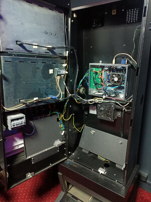 Zdjęcie przedstawia otwarty automat do gier hazardowych, umieszczony w pomieszczeniu przy ścianie.