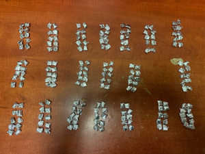 Zdjęcie przedstawia foliowe zawiniątka ułożone na brązowym blacie biurka.