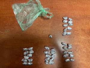 Zdjęcie przedstawia foliowe zawiniątka ułożone na brązowym blacie biurka obok zielonej foliowej reklamówki.