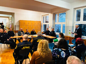 Zdjęcie przedstawia przedstawicieli policji, straży miejskiej i urzędu dzielnicy siedzących w jednym długim stole.