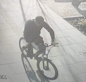 Zdjęcie jest w kolorach szarych, przedstawia osobę jadącą rowerem.