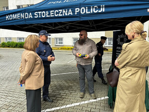 Zdjęcie przedstawia osoby stojące pod niebieskim zadaszeniem.