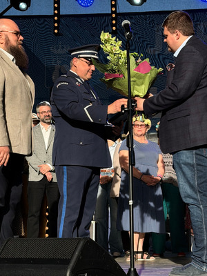 Zdjęcie przedstawia policjanta w galowym mundurze odbierającego nagrodę.