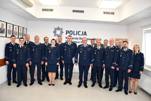 Zdjęcie przedstawia umundurowanych policjantów stojących na tle białej ściany.