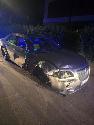 Zdjęcie przedstawia uszkodzony srebrny pojazd osobowy marki Lancia, bez prawego przedniego koła.