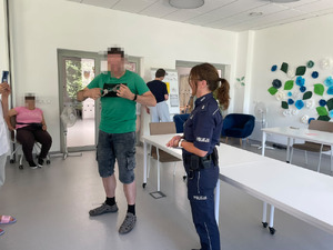 Zdjęcie przedstawia policjantkę stojącą obok mężczyzny trzymającego w dłoniach kajdanki.