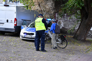 Zdjęcie przedstawia dwóch policjantów kontrolujących rowerzystę.