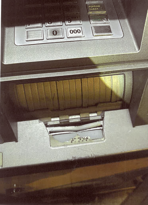 Zdjęcie przedstawia front bankomatu z uszkodzoną kasetką.