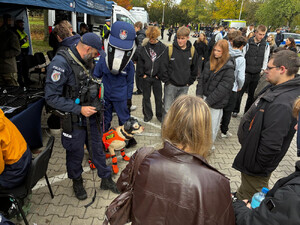 Zdjęcie przedstawia policjanta z psem służbowym i stojącą obok nich młodzież.