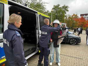 Zdjęcie przedstawia policjantów ubierających młodego chłopaka w umundurowanie do zabezpieczeń.